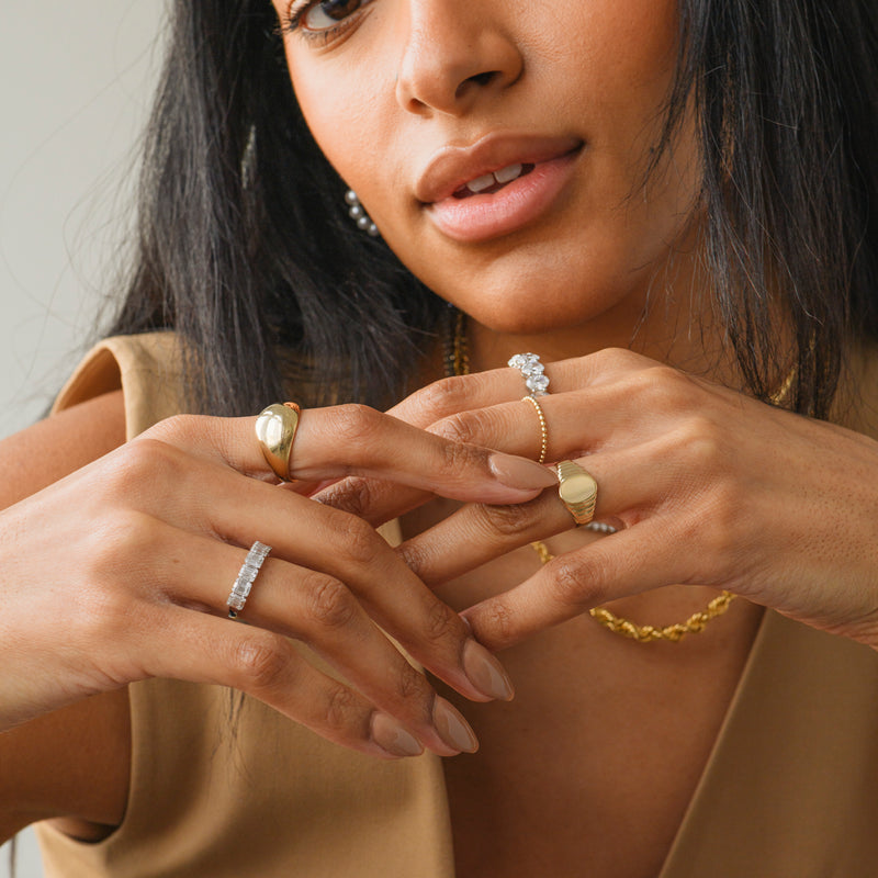 14k gold beaded ring on hand with styled fashion rings.